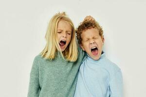 Photo of two children in multi-colored sweaters posing for fun light background