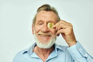 Photo of retired old man finance gold coins bitcoin near face light background