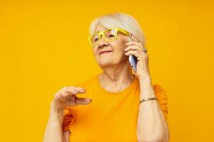 elderly woman happy lifestyle in yellow t-shirts with phone close-up emotions photo