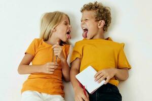 dos alegre niños mentira en el piso con libretas y lapices aislado antecedentes inalterado foto