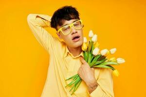 un joven hombre en amarillo lentes con un ramo de flores de flores fiesta inalterado foto