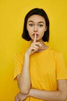 short haired brunette yellow t-shirt summer style hand gesture yellow background photo