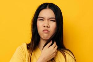 woman with Asian appearance in a yellow t-shirt holding his head discontent yellow background unaltered photo