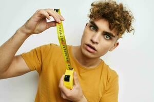 kinky guy measuring tape measure in yellow t-shirt light background photo