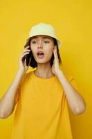 joven hermosa mujer en un amarillo sombrero juventud estilo casual hablando en el teléfono aislado antecedentes foto