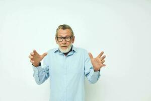 Portrait of happy senior man in blue shirts gestures with his hands light background photo