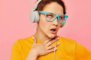 cheerful woman wearing blue glasses listening to music on headphones isolated backgrounds unaltered photo