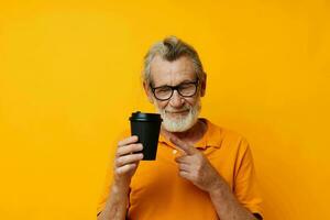 Senior grey-haired man with black disposable cup yellow background photo