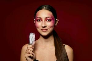 fashionable woman pink face makeup posing attractive look with a comb pink background unaltered photo