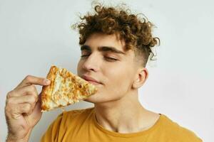 handsome guy eating pizza posing close-up light background photo