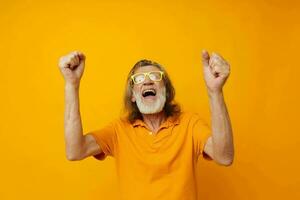 Portrait elderly man yellow t-shirt and glasses posing isolated background photo