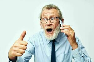 old man with phone in studio on white background shows thumb up photo