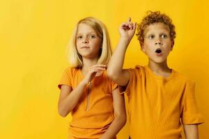 cheerful children in yellow t-shirts standing side by side childhood emotions yellow background photo