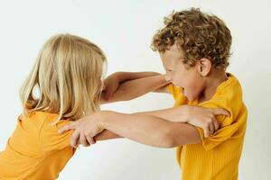 Small children in yellow t-shirts standing side by side childhood emotions light background unaltered photo