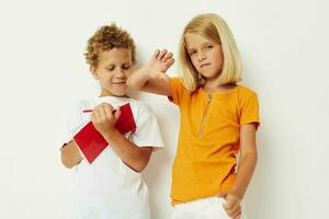 imagen de positivo chico y niña divertido en vistoso camisetas con un bloc aislado antecedentes inalterado foto