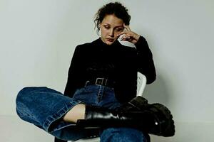 alegre mujer sentado en un silla en un negro chaqueta Moda posando estilo de vida inalterado foto