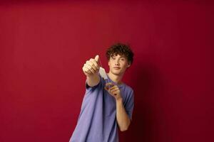 A young man in purple t-shirts medical mask in hands safety isolated background unaltered photo