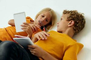 Cute preschool kids drawing in notebooks lying on the floor isolated background unaltered photo