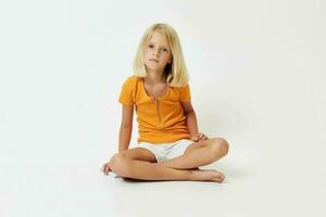 little girl with blond hair gesturing with her hands while sitting on the floor photo