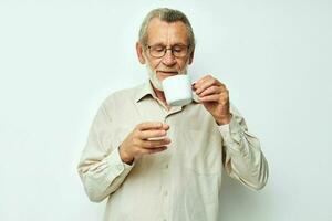 elderly man drinking from a mug on a white background and smiling photo