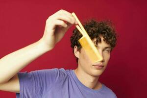 portrait of a young curly man posing hairbrush personal care red background photo