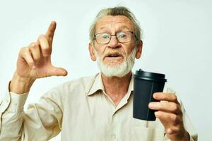 retrato de contento mayor hombre con un gris barba en un camisa y lentes ligero antecedentes foto