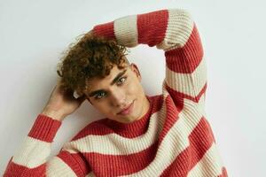 atractivo hombre en un a rayas suéter posando ligero antecedentes foto