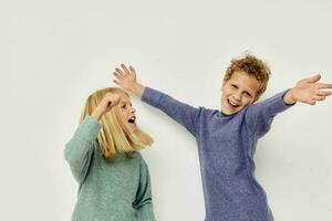 Cute stylish children in multi-colored sweaters posing for fun light background photo