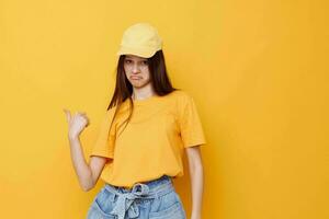 young beautiful woman posing in a yellow T-shirt and cap yellow background photo