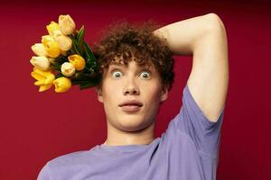 young guy holding a yellow bouquet of flowers purple t-shirts isolated background unaltered photo