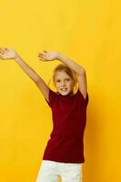 cheerful girl with blond hair gesturing with her hands yellow background photo