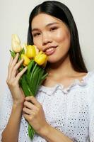 encantador joven asiático mujer en un blanco camisa flores primavera posando estudio modelo inalterado foto