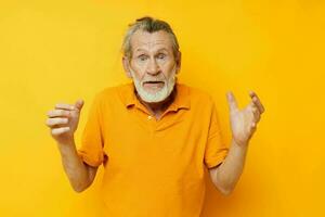 Portrait of happy senior man yellow shirt posing emotions yellow background photo