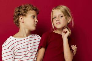 Portrait of cute children emotions stand side by side in everyday clothes red background photo