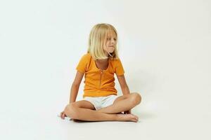 little girl with blond hair gesturing with her hands while sitting on the floor photo