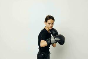 young woman in black sports uniform boxing gloves posing isolated background photo