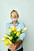 elderly man a bouquet of flowers with glasses as a gift light background photo