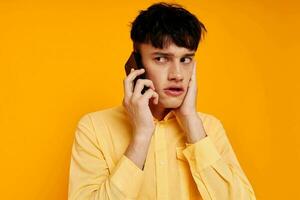 handsome man in a yellow shirt talking on the phone close-up photo