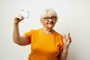 smiling elderly woman in a yellow t-shirt posing communication by phone close-up emotions photo