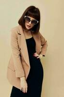 photo pretty woman in a beige jacket elegant style sunglasses light background