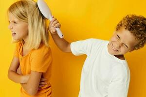 a boy with a comb combing a girl's hair yellow background photo