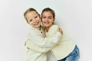 two little girls in sweaters posing childhood light background photo