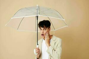 a man with an open umbrella in a jacket protection from the rain beige background photo