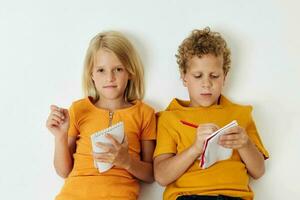 two joyful children lie on the floor with notepads and pencils childhood lifestyle unaltered photo