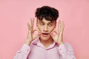handsome guy gestures with hands emotions hairstyle fashion pink background unaltered photo