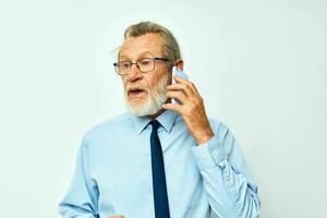 Photo of retired old man in a shirt with a tie talking on the phone isolated background