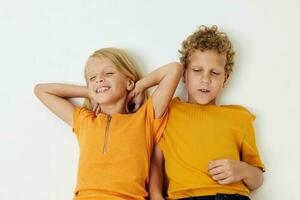 chico y niña mentira en un blanco antecedentes en amarillo camisetas emociones foto