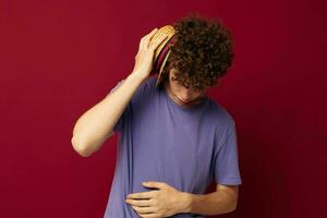 A young man in Hat purple t-shirts posing emotions red background unaltered photo