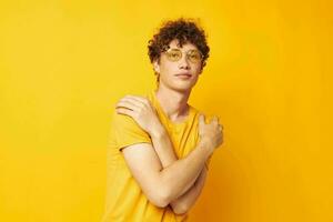 portrait of a young curly man wearing stylish glasses yellow t-shirt posing Lifestyle unaltered photo