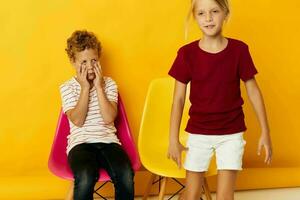 Small children childhood sitting on chairs together on colored background photo